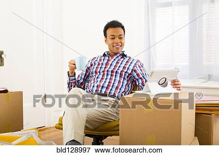 Mixed race man using digital tablet and having cup of coffee View Large Photo Image Stock Photo - Mixed race man using digital tablet and having cup of coffee. Fotosearch