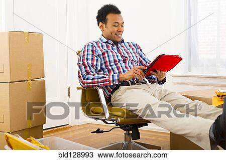 Mixed race man using digital tablet in new home View Large Photo Image Stock Image - Mixed race man using digital tablet in new home. Fotosearch
