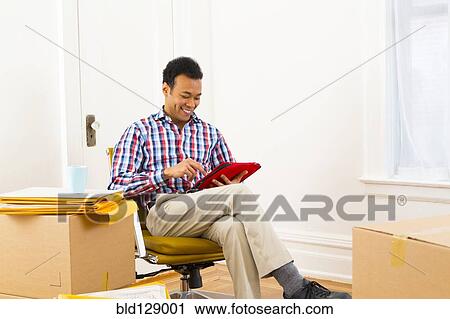Mixed race man using digital tablet in new home View Large Photo Image Stock Image - Mixed race man using digital tablet in new home. Fotosearch