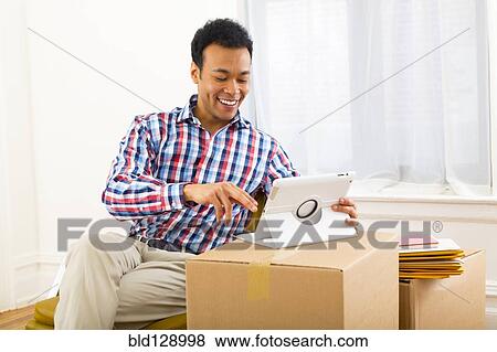 Stock Photo - Mixed race man using digital tablet. Fotosearch