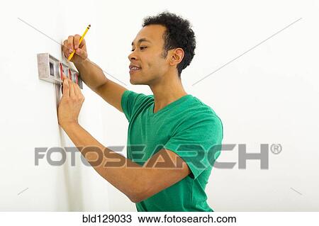 Mixed race man using level on wall View Large Photo Image Stock Image - Mixed race man using level on wall. Fotosearch