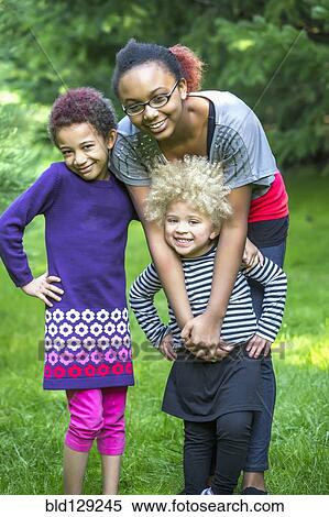 Stock Photography - Mixed race sisters smiling together outdoors. Fotosearch