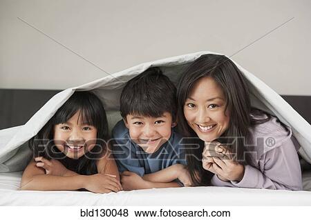 Mother and children laying under bed covers View Large Photo Image Stock Photo - Mother and children laying under bed covers. Fotosearch