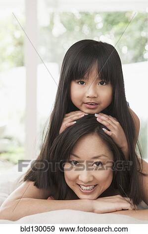 Stock Photo - Mother and daughter laying on bed. Fotosearch