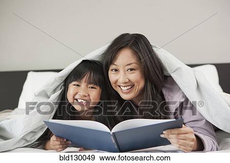 Mother and daughter reading in bed View Large Photo Image Stock Photo - Mother and daughter reading in bed. Fotosearch