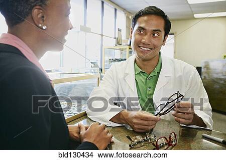Optometrist talking to patient in office View Large Photo Image Picture - Optometrist talking to patient in office. Fotosearch