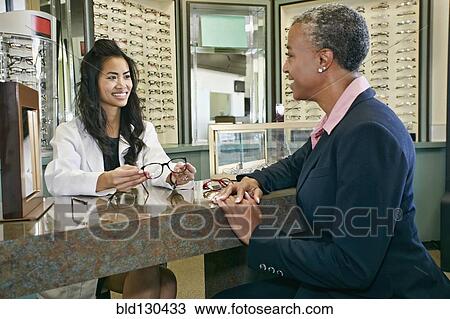 Stock Image - Optometrist talking to patient in office. Fotosearch