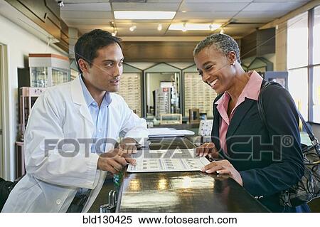 Optometrist talking to patient in office View Large Photo Image Stock Photography - Optometrist talking to patient in office. Fotosearch