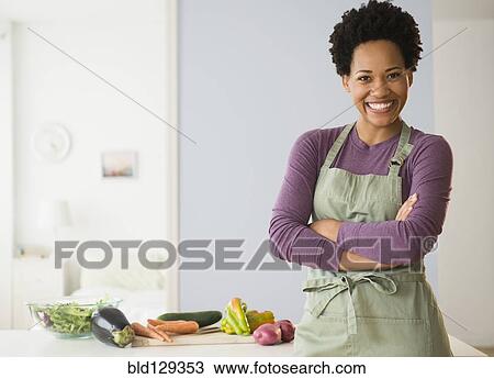 Stock Image - Portrait of black woman cooking in kitchen. Fotosearch