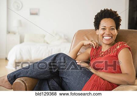 Stock Photo - Portrait of smiling Black woman in armchair. Fotosearch
