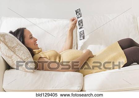 Stock Photography - Pregnant Hispanic woman admiring ultrasound photos. Fotosearch