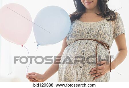 Pregnant Hispanic woman carrying balloon View Large Photo Image Stock Photo - Pregnant Hispanic woman carrying balloon. Fotosearch