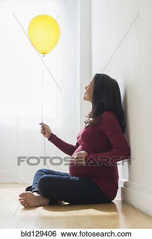 Stock Photograph - Pregnant Hispanic woman holding balloon. Fotosearch