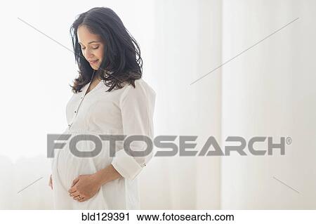 Stock Image - Pregnant Hispanic woman touching her belly. Fotosearch