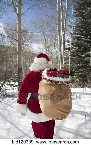 Santa Claus carrying Christmas gifts in snowy woods View Large Photo Image Stock Photo - Santa Claus carrying Christmas gifts in snowy woods. Fotosearch