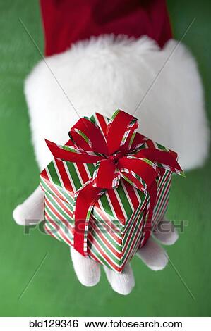 Stock Photograph - Santa Claus holding Christmas gift. Fotosearch