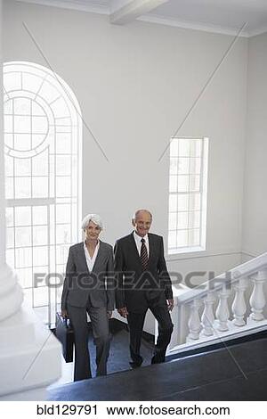 Stock Image - Senior Caucasian business people climbing office steps. Fotosearch