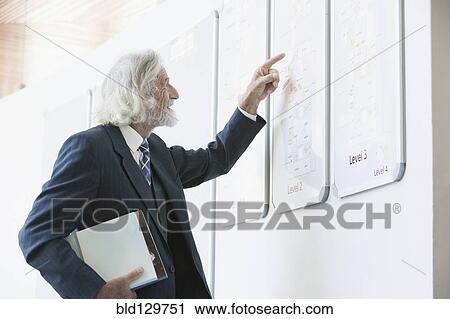 Stock Image - Senior Caucasian businessman reading directory. Fotosearch