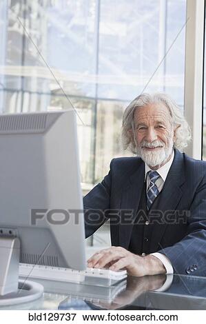 Stock Photo - Senior Caucasian businessman working at desk. Fotosearch