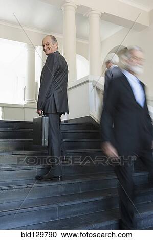 Stock Image - Senior Caucasian businessmen climbing office steps. Fotosearch