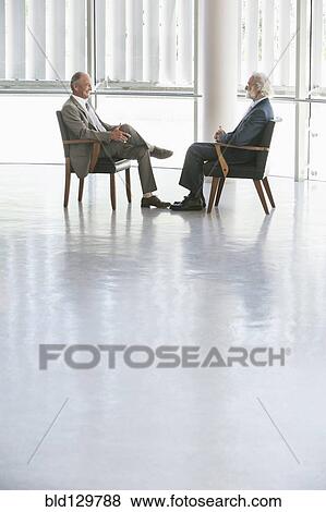 Senior Caucasian businessmen talking in office View Large Photo Image Stock Photo - Senior Caucasian businessmen talking in office. Fotosearch