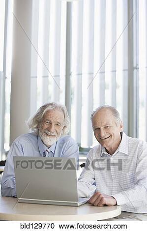 Stock Image - Senior Caucasian businessmen working together in office. Fotosearch
