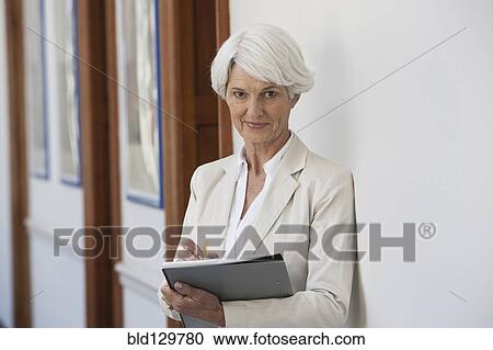 Stock Image - Senior Caucasian businesswoman making notes in office. Fotosearch