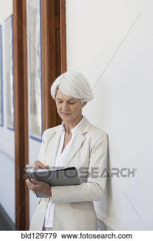 Stock Photo - Senior Caucasian businesswoman making notes in office. Fotosearch