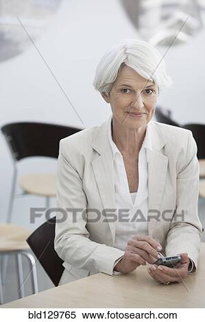 Senior Caucasian businesswoman using cell phone in cafe View Large Photo Image Stock Photography - Senior Caucasian businesswoman using cell phone in cafe. Fotosearch