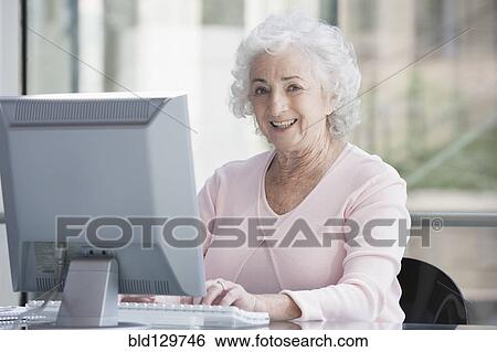 Stock Photograph - Senior Caucasian businesswoman working at desk. Fotosearch