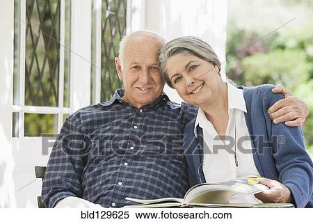 Stock Photography - Senior Caucasian couple reading outdoors. Fotosearch