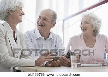 Stock Photograph - Senior Caucasian friends laughing in cafe. Fotosearch
