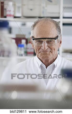 Stock Image - Senior Caucasian scientist smiling in lab. Fotosearch