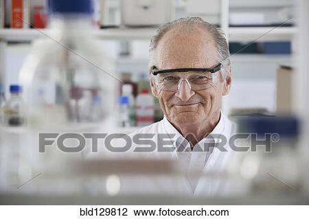 Stock Image - Senior Caucasian scientist smiling in lab. Fotosearch