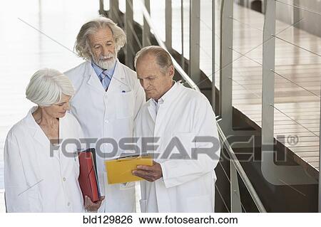 Stock Photograph - Senior Caucasian scientists talking in office. Fotosearch