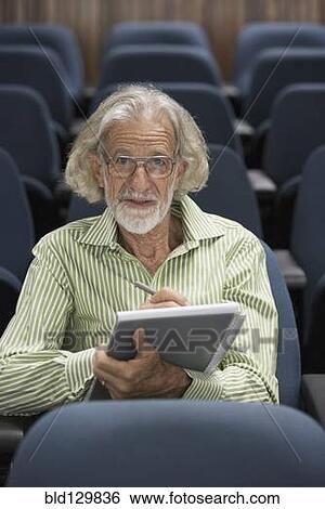 Stock Photograph - Senior Caucasian student taking notes in classroom. Fotosearch
