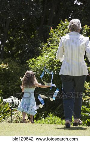 Stock Image - Senior Caucasian woman and granddaughter playing outdoors. Fotosearch