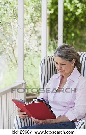 Stock Photo - Senior Caucasian woman reading on porch. Fotosearch