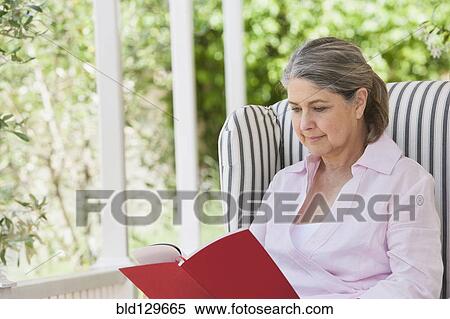 Stock Photography - Senior Caucasian woman reading on porch. Fotosearch