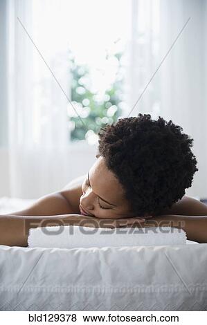 Stock Photo - Serene Black woman laying on massage table. Fotosearch