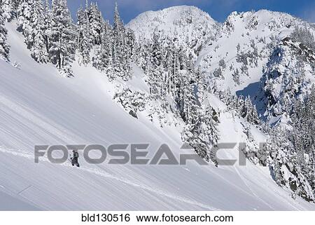 Stock Photograph - Snowshoer walking up snowy hillside. Fotosearch