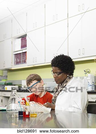 Stock Image - Student and teacher working in chemistry lab. Fotosearch