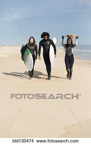 Surfers carrying boards on beach View Large Photo Image Picture - Surfers carrying boards on beach. Fotosearch