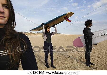 Surfers carrying boards on beach View Large Photo Image Stock Photography - Surfers carrying boards on beach. Fotosearch