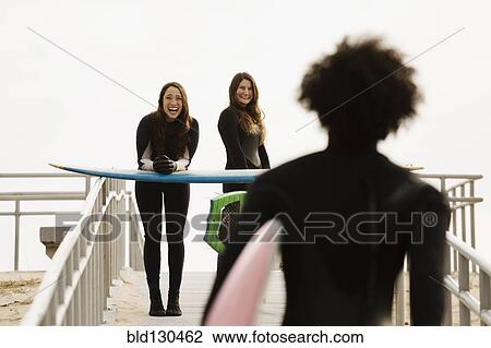 Stock Image - Surfers carrying boards to beach. Fotosearch