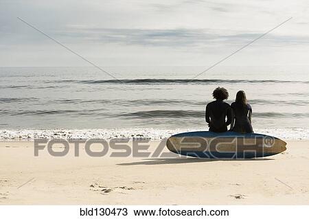 Surfers sitting on board on beach View Large Photo Image Stock Image - Surfers sitting on board on beach. Fotosearch
