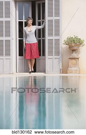 Woman in doorway overlooking swimming pool View Large Photo Image Stock Image - Woman in doorway overlooking swimming pool. Fotosearch