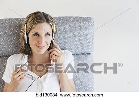 Woman listening to headphones in armchair View Large Photo Image Picture - Woman listening to headphones in armchair. Fotosearch
