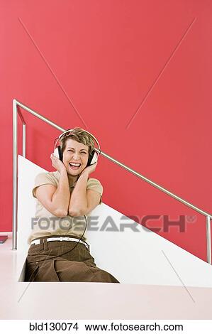 Woman listening to headphones on stairs View Large Photo Image Picture - Woman listening to headphones on stairs. Fotosearch