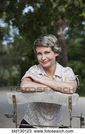 Stock Image - Woman sitting in chair outdoors. Fotosearch
